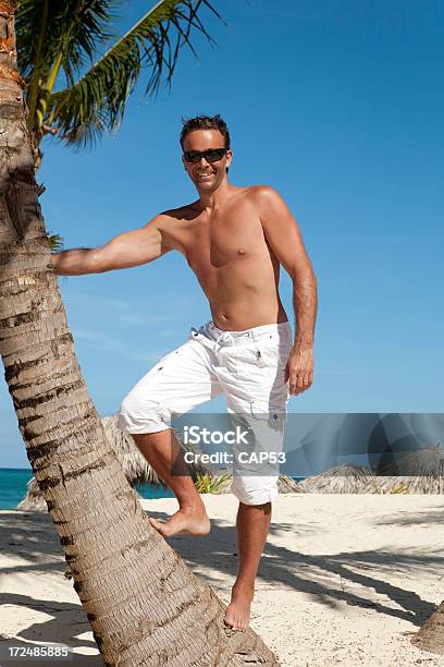 Piękny Człowiek Pozujących Na Palm Tree - zdjęcia stockowe i więcej obrazów Biały - Biały, Dorosły, Drzewo