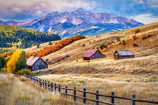 Boulder Colorado, USA -October 23, 2023: An Abandoned Barn sits outside Boulder Colorado. Wispy Cirrus clouds, Flatirons Rock Formations and Autumn Foliage create a Tranquil Rural Scene.