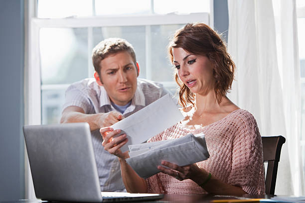 Home finances Couple at home paying bills, looking worried.  Focus on woman (20s). Sc0601 stock pictures, royalty-free photos & images