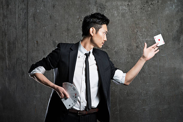Magician doing card tricks An Asian magician performing card tricks against a grungy background  magic trick photos stock pictures, royalty-free photos & images