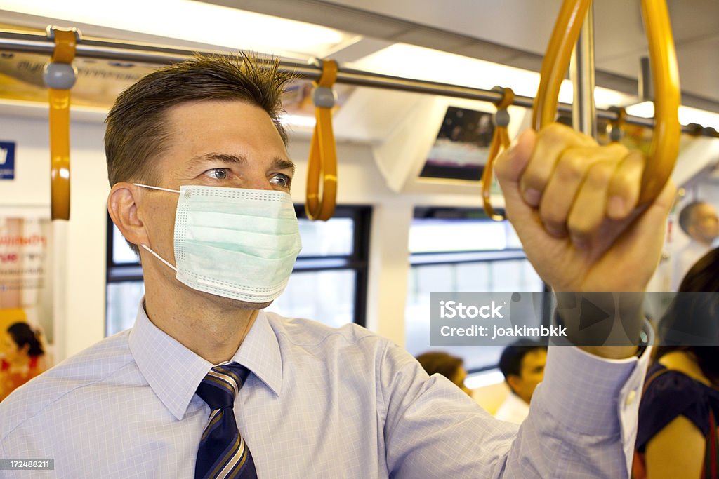 Maturo Uomo d'affari indossando maschera protettiva in treno - Foto stock royalty-free di Accudire