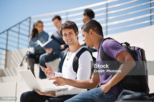 Hombre Con Ordenador Portátil Hablando De Estudiantes En El Campus Foto de stock y más banco de imágenes de 18-19 años