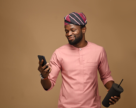 Portrait of an attractive and happy young male freelancer clenching his fist in the middle of a phone conversation, celebrating the good news that he received. Space for text and advertising.