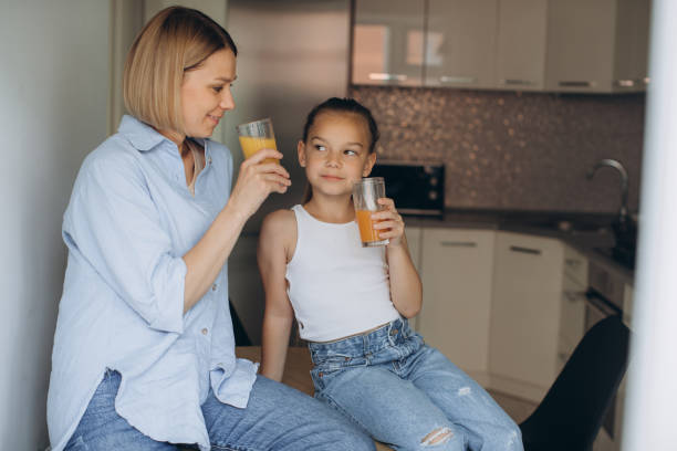 istock Mother and daughter drink fresh juice while sitting in the kitchen. 1724963901