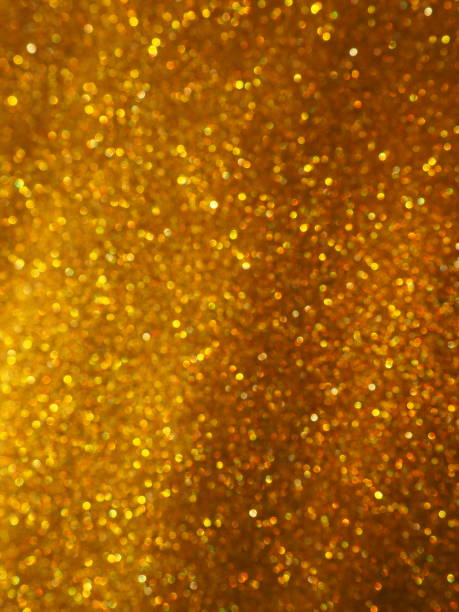 Bokeh light of gold glitters. Golden glitter texture background. Sparkling glitter wrapping paper with sequins and sparkles. Festive golden bokeh and glitter. Diagonal stripes and waves stock photo