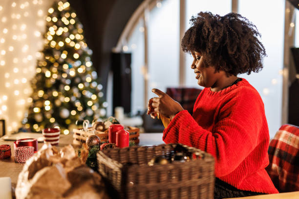 istock Charming young Black woman decorating a Christmas wreath 1724978689