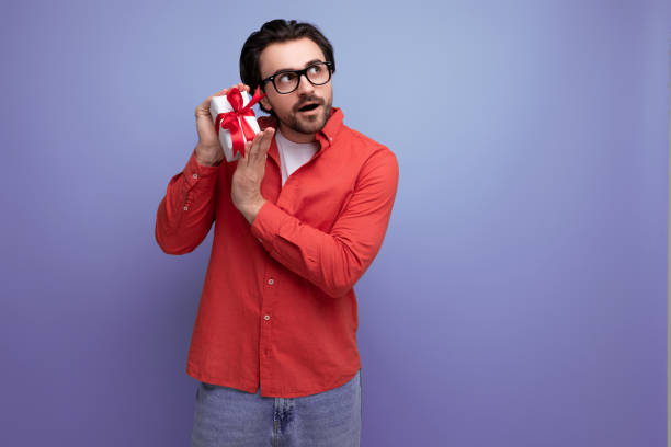 charming positive 30s man in a red shirt cutely guesses what was presented to him in a box charming positive 30s man in a red shirt cutely guesses what was presented to him in a box. cutely stock pictures, royalty-free photos & images