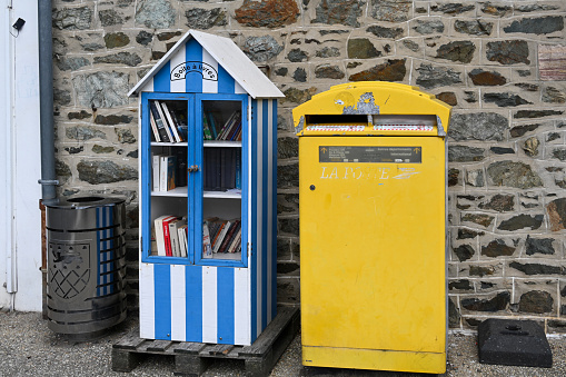 Pléneuf-Val-André, France August 22, 2023 - Book sharing box next to a public mailbox in downtown Pléneuf-Val-André, Brittany.