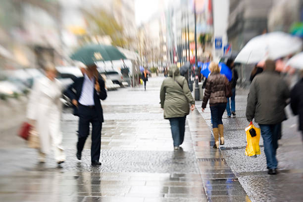 Blurry image of people walking on the pavement in the rain People walking with umbrellas on a shopping street in Vienna (Kärnterstrasse), taken with lensbaby yt stock pictures, royalty-free photos & images