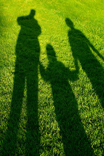 Shadow of two people putting their hands together to make a heart shape on concrete background, copy space, love concept
