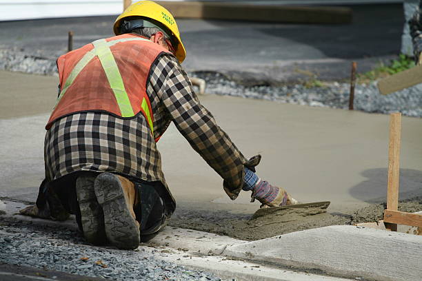 A construction worker paving the sidewalk with concrete
