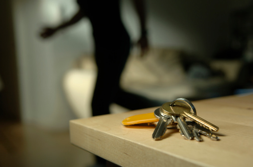 bunch of keys on wooden table with shadowy running figure in background - shallow depth of field