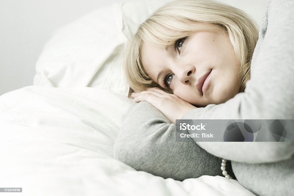 girl thinking in bed Shot of a young attractive girl lying in bed thinking and looking sorta sad. Very brightly lit 16-17 Years Stock Photo