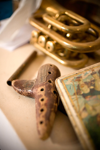 Small ocarina instrument (hand made product) and a trumpet in background.