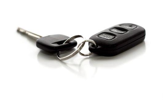 A car key with remote control.  Functions include Lock, Unlock, and Hatch Glass.  Narrow depth of field with focus on closest portion of key and remote.  Isolated on white background.