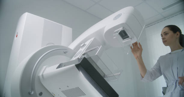 istock Female doctor uses computer, then sets up mammogram machine for patient 1725161725