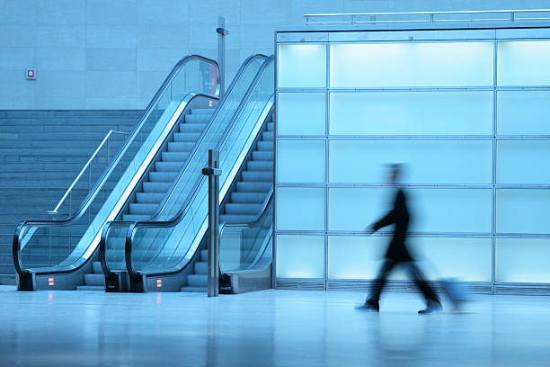 istock Businessman pulling luggage in corridor with escalators blurred motion 172517332