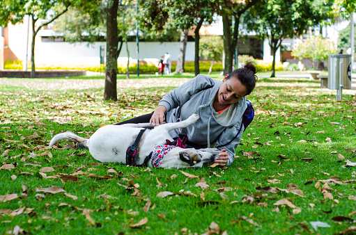 middle aged woman playing with dog in public park