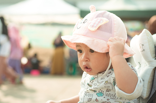 Headshot of a cute Asian baby girl wearing a hat outdoor