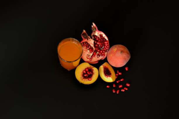 黒い背景にフルーツジュースと桃とザクロの種のガラス。 - nectarine fruit full length cross section ストックフォトと画像