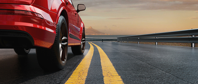 Close-up side view of an red luxury sports car on the road as the sun sets.3d render and illustration.