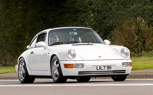 Bicester,Oxon.,UK - Oct 8th 2023: 1990 white PORSCHE 911 CARRERA 4 classic car driving on an English country road.