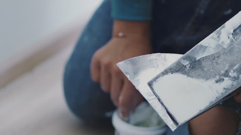 Man mixes putty on a white wall to fill cracks