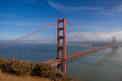 Golden Gate Bridge with San Francisco skyline in background. Travel destination, architecture, symmetry, dark