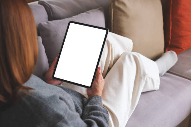 istock Mockup image of a woman holding digital tablet with blank desktop screen while lying on a sofa at home 1725356220