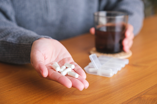 Closeup image of hands holding pills and a glass of water