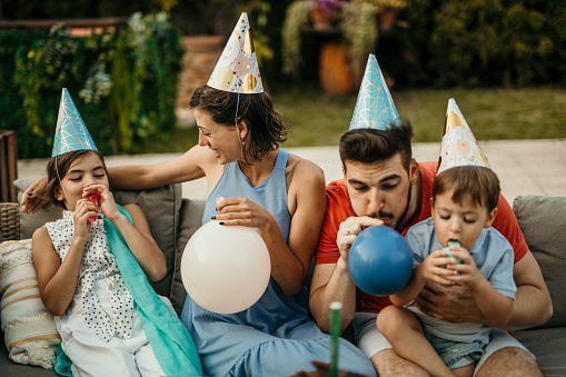 A joyful family gathers around a beautifully decorated birthday table in a lush garden setting, sharing smiles and laughter as they celebrate a special occasion with a delicious cake