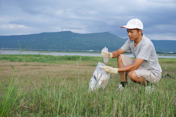 istock asian men collecting garbage in public park. 1725399648