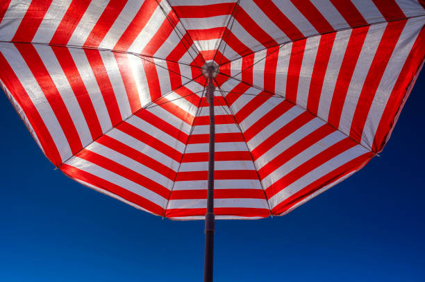 istock White red parasol against blue sky background on beach, vacation and sun protection theme 1725408086