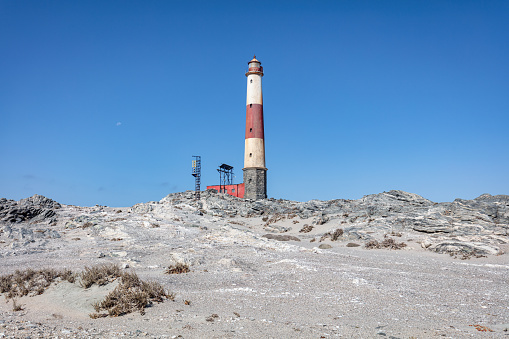 Fishing village of Farol in the Culatra island with its traditional houses in a sunny day with the famous lighthouse in the background. Olhao Algarve region, Portugal.