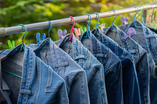 A side view image of freshly washed denim jeans hanging on a clothesline on nature background.