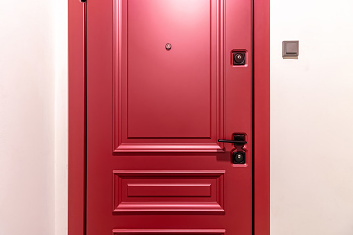 The close up image of a newly installed front door on a home. The door is a deep red, berry color. There is a matching storm door.