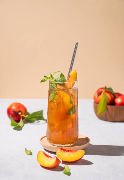 glace aux pêches rafraîchissante et thé à la menthe. boisson estivale froide maison végétalienne sur grand verre sur fond clair avec des fruits frais et des ombres. - georgia peach photos et images de collection