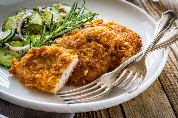 istock Breaded seared chicken cutlets with fresh vegetable salad on wooden table 1725497383