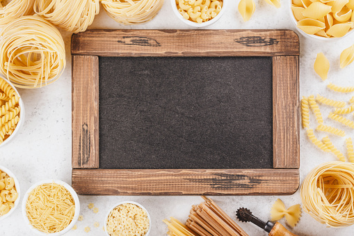 Pasta month. Assortment of uncooked pasta and noodles. Italian food culinary concept. Collection of different raw pasta on cooking table