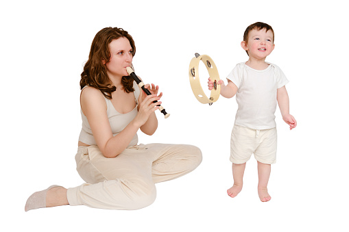 Happy baby with mother play musical instruments on studio, isolated on white background. Portrait of a smiling child with mom and playing the flute