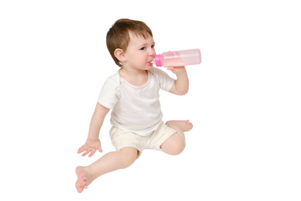 Happy baby drinks milk from bottle on studio, isolated on white background. Resting child eats formula, isolated on white background. Kid about two years old (one year nine months)