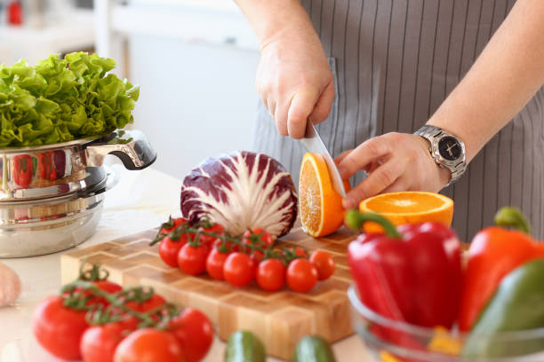 istock Closeup of chef hands cutting an orange on cutting board in kitchen 1725516618