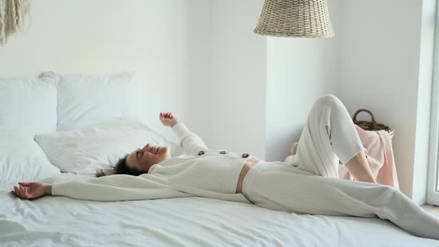 Relaxed Woman Collapsing onto Bed in the Bedroom