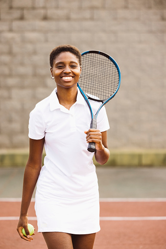 Portrait of a young beautiful women with tennis clothes and racket in a tennis court ready to play a game.