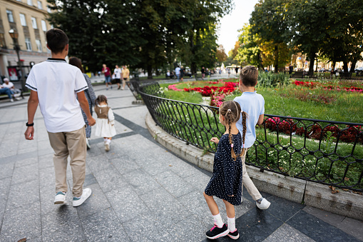 Back view of family with four kids walking in Lviv city, Ukraine.