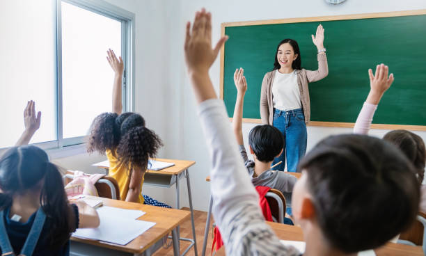 istock Multicultural group of students raising hands in class on lecture education, elementary school, learning people concept. Group team work of school kids with teacher sit in classroom and raising hands 1725561255