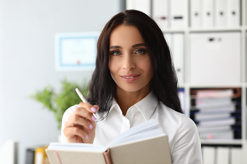 Young woman keeps diary in notebook, recalls memories and makes to-do list. People lifestyle concept and future planning