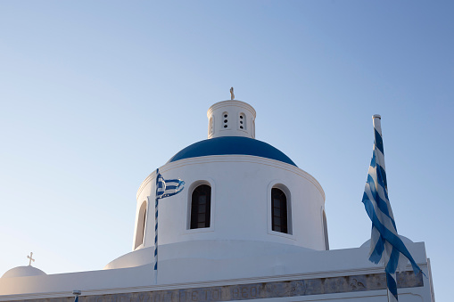 Blue dome architectural detail with Greek flags in a beautiful church in Santorini