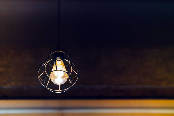 istock Light bulbs hanging from the vintage ceiling glow a golden yellow. Copy space. 1725591662