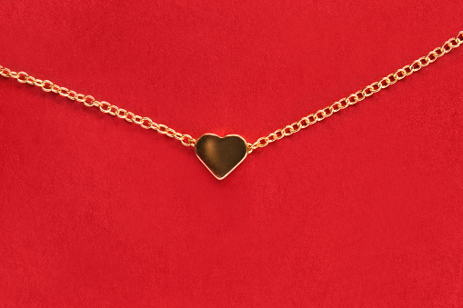 Golden heart necklace on red studio background